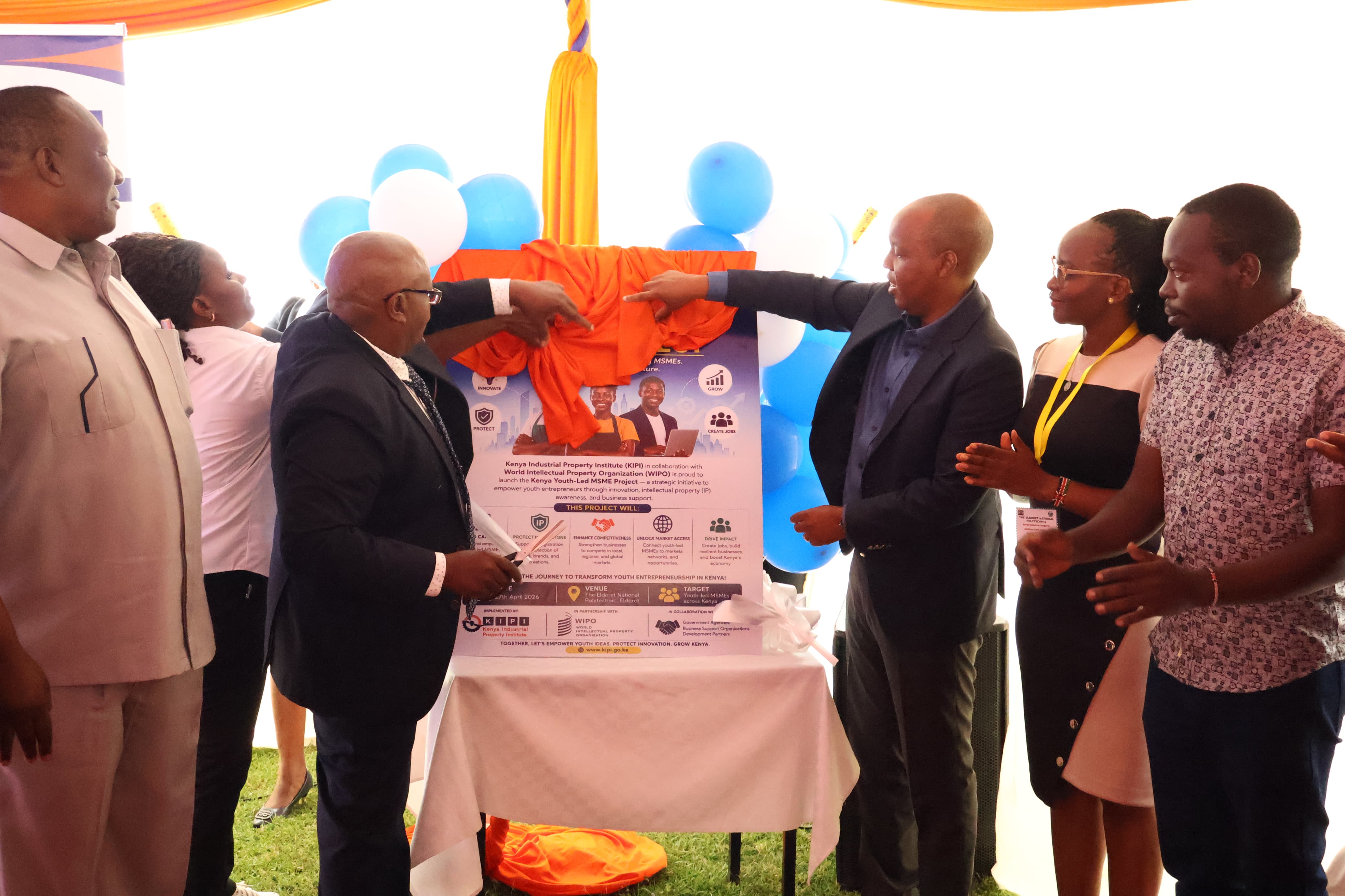 Karanja Njora (Left), Secretary Administration, assisted by Allan Kosgey (Right),KIPI Board Chairman, launch the Youth-led MSMEs Project during the Celebrations at the Eldoret National Polytechnic