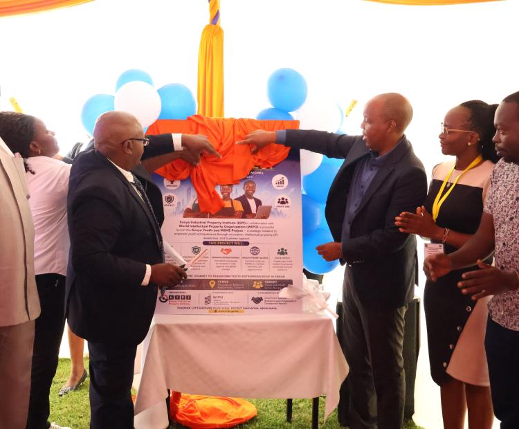 Karanja Njora (Left), Secretary Administration, assisted by Allan Kosgey (Right),KIPI Board Chairman, launch the Youth-led MSMEs Project during the Celebrations at the Eldoret National Polytechnic